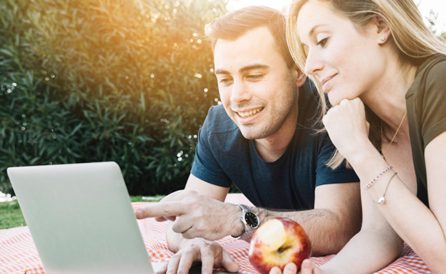 זוג בפיקניק צופה על צג של מחשב נייד